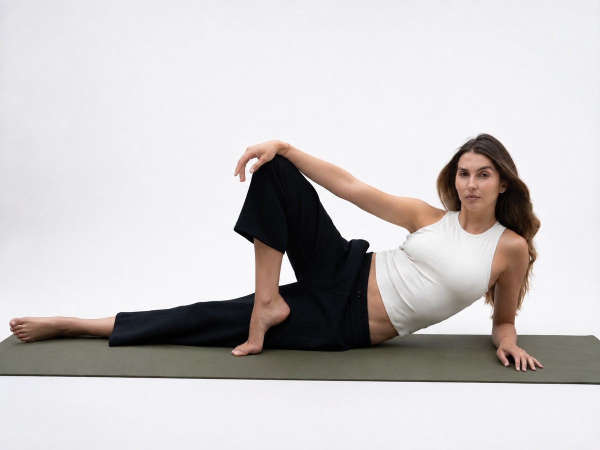 Top Riva en ivory con pantalón negro, postura de yoga sobre el mat